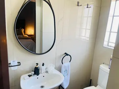 a bathroom with a sink and a mirror at Mnqobi Lifestyle Apartments in Nelspruit