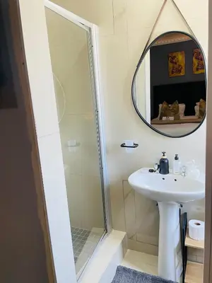 a bathroom with a shower and a sink and a mirror at Mnqobi Lifestyle Apartments in Nelspruit