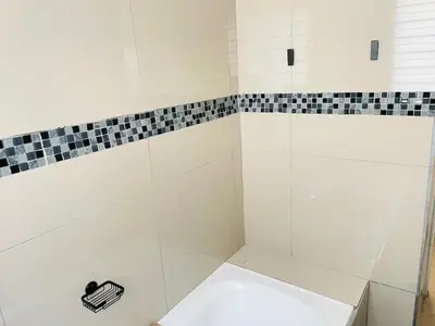 a white shower with black and white tiles on the wall at Mnqobi Lifestyle Apartments in Nelspruit