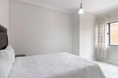 a white bedroom with a bed and a window at The blyde lovely 1 bedroom in Pretoria