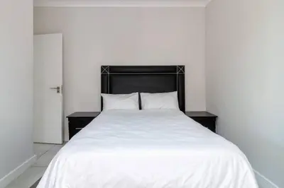 a white bed with a black headboard in a room at The blyde lovely 1 bedroom in Pretoria