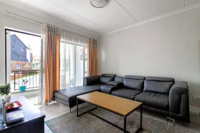 a living room with a black couch and a table at The blyde lovely 1 bedroom in Pretoria