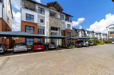 a parking lot with cars parked in front of a building at The blyde lovely 1 bedroom in Pretoria