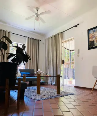 a living room with a couch and a ceiling fan at The White House in Hartbeespoort