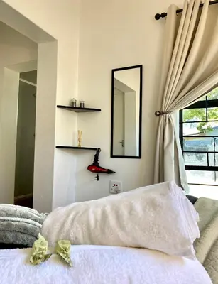a bedroom with a bed with a mirror and a window at The White House in Hartbeespoort