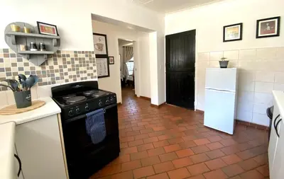 a kitchen with a black stove and a refrigerator at The White House in Hartbeespoort