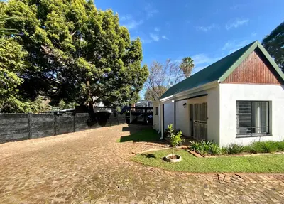 a small white building with a tree and a fence at The White House in Hartbeespoort