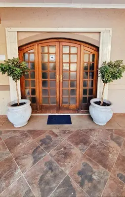 two potted trees in pots in front of a door at Alpha B Lodging in Thabazimbi