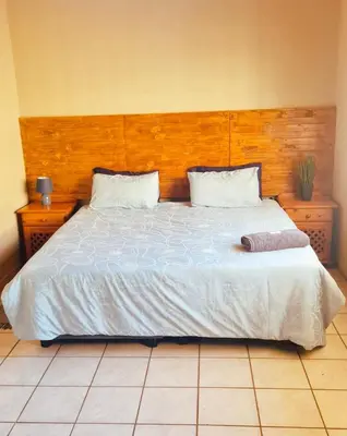 a bedroom with a large bed with a wooden headboard at Alpha B Lodging in Thabazimbi