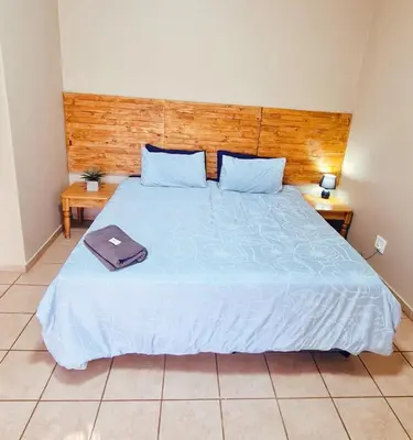 a bedroom with a large blue bed with two tables at Alpha B Lodging in Thabazimbi