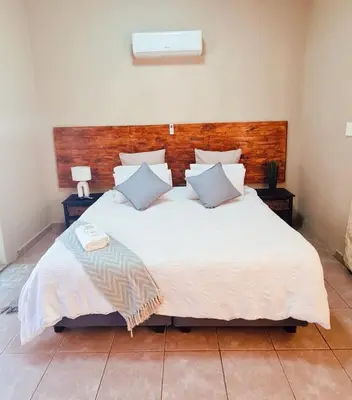 a bedroom with a large white bed with a wooden headboard at Alpha B Lodging in Thabazimbi