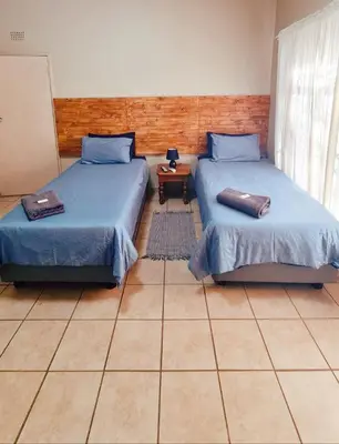 a room with two beds and a table at Alpha B Lodging in Thabazimbi