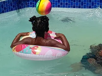 a woman in the water on a raft with a ball on her head at Cozy guesthouse springs in Springs