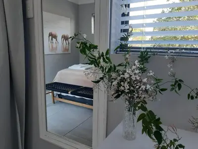 a mirror in a room with a bed and flowers at The Bird Hide Luxury Self catering Chalets in White River