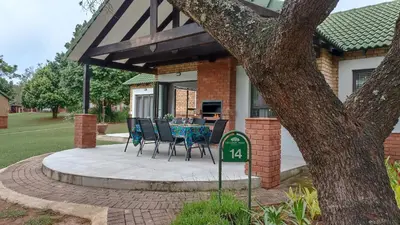 a patio with chairs and a table in front of a house at The Bird Hide Luxury Self catering Chalets in White River