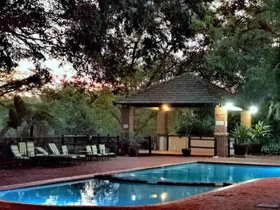 a swimming pool with chairs and a gazebo at The Bird Hide Luxury Self catering Chalets in White River