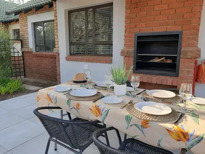 a table with plates and chairs and a fireplace at The Bird Hide Luxury Self catering Chalets in White River