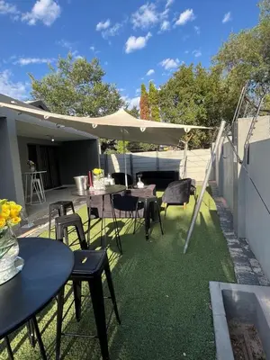 a patio with tables and chairs and an umbrella at Midrand Air B and B House in Midrand