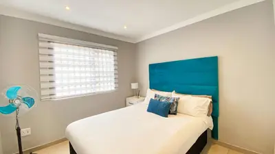 a bedroom with a large bed with a blue headboard at Midrand Air B and B House in Midrand