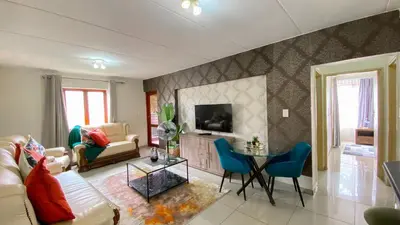 a living room with a couch a table and a tv at Midrand Air B and B Apartment in Midrand