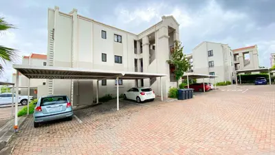 a parking lot with cars parked in front of a building at Midrand Air B and B Apartment in Midrand