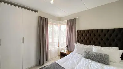 a bedroom with a large bed and a window at Midrand Air B and B Apartment in Midrand