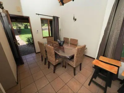 a dining room with a wooden table and chairs at Kruger Park Lodge Unit 550 With Private Pool in Hazyview