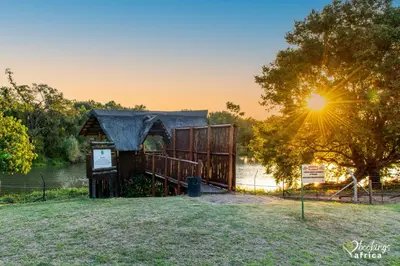 a wooden kiosk in a park with the sun setting at Kruger Park Lodge Unit 550 With Private Pool in Hazyview