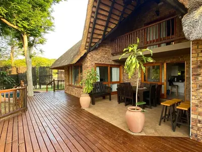 a wooden deck with a house with a table and chairs at Kruger Park Lodge Unit 550 With Private Pool in Hazyview