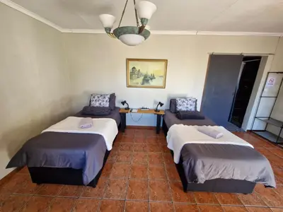 a room with two beds and a table in it at 29B Zebra Street - InHimwe Guesthouse in Polokwane