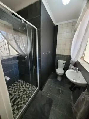 a bathroom with a shower and a toilet and a sink at 29B Zebra Street - InHimwe Guesthouse in Polokwane
