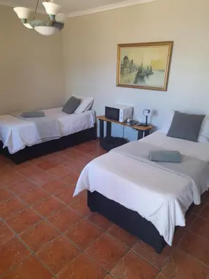 a room with two beds and a table and a picture at 29B Zebra Street - InHimwe Guesthouse in Polokwane