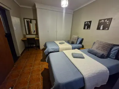 a hotel room with two beds and a desk at 29B Zebra Street - InHimwe Guesthouse in Polokwane