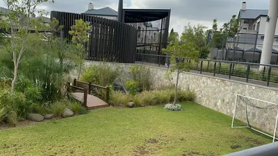 a garden with a bench and a retaining wall at Fealathome Apartment in Midrand