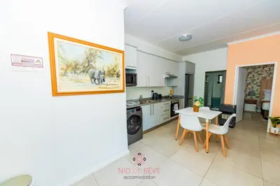 a kitchen and a living room with a table and chairs at Nid de Rêve Accommodation in Midrand