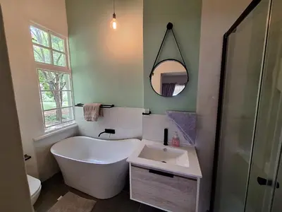 a bathroom with a tub and a sink and a mirror at Oude Post Guesthouse and Cottage - The Old Postmaster's House in Lydenburg