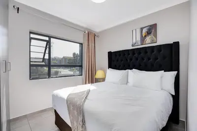 a bedroom with a large bed with a black headboard at Opposite Mall of Africa Inn in Midrand