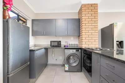 a kitchen with a washing machine and a washer at Opposite Mall of Africa Inn in Midrand