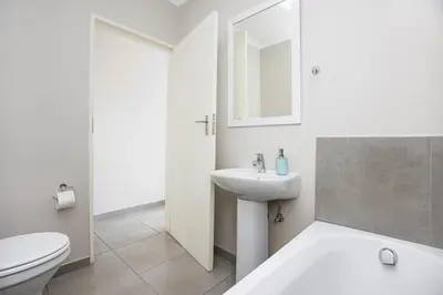 a white bathroom with a sink and a toilet at Opposite Mall of Africa Inn in Midrand