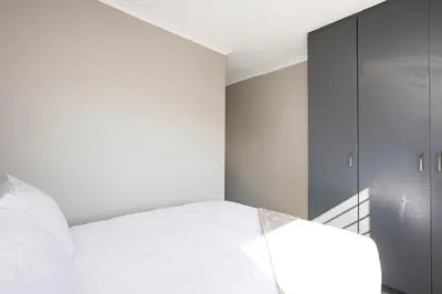 a bedroom with a white bed and a mirror at Opposite Mall of Africa Inn in Midrand