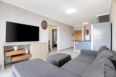 a living room with a couch and a flat screen tv at Opposite Mall of Africa Inn in Midrand