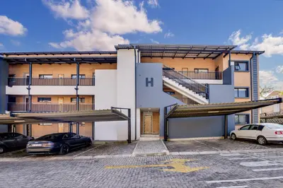 a building with stairs and cars parked in a parking lot at Opposite Mall of Africa Inn in Midrand