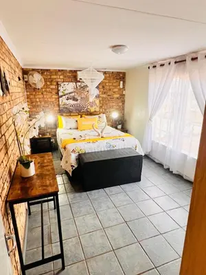 a bedroom with a bed and a brick wall at Bliss in Marloth Park