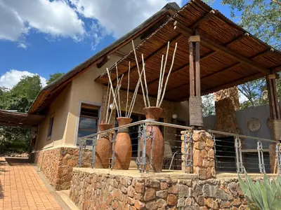 a house with a bunch of vases in front of it at Pumula Bush Chalet in Mabula