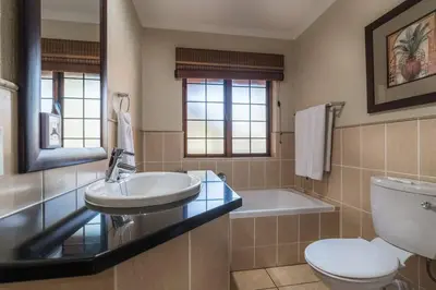 a bathroom with a sink and a toilet and a tub at Kruger Park Lodge unit 34 in Hazyview