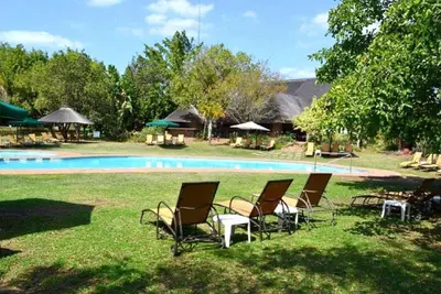 a group of chairs sitting in the grass near a pool at Kruger Park Lodge unit 34 in Hazyview