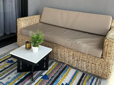 a wicker couch sitting in a living room with a table at Ellipse Waterfall Luxury Apartments in Midrand