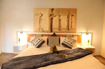 a bedroom with a large bed with a painting on the wall at Villa Ticino Guest House in Sabie
