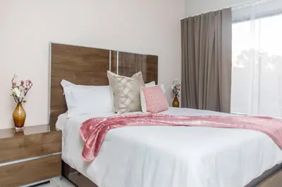 a bedroom with a large bed with a pink blanket on it at Fore's Luxurious Home in Midrand