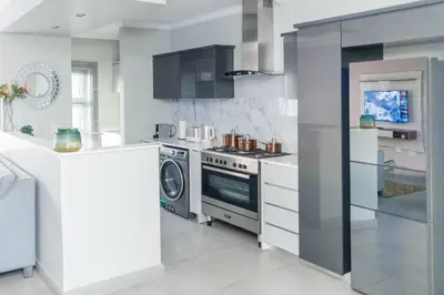 a white kitchen with a stove and a dishwasher at Fore's Luxurious Home in Midrand